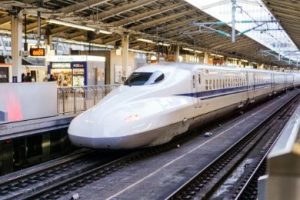 While Shinkansen (bullet train) with a blue stripe on the side at a train platform. Train Etiquette.