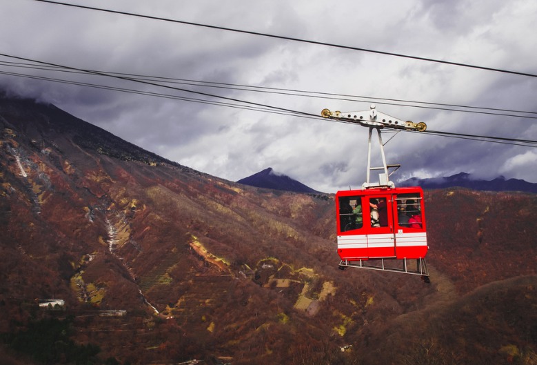 The red car of Akechidaira Ropeway, with mountain views in the background