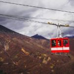 The red car of Akechidaira Ropeway, with mountain views in the background