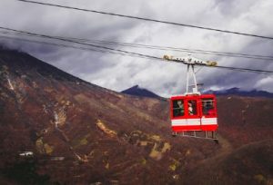 The red car of Akechidaira Ropeway, with mountain views in the background