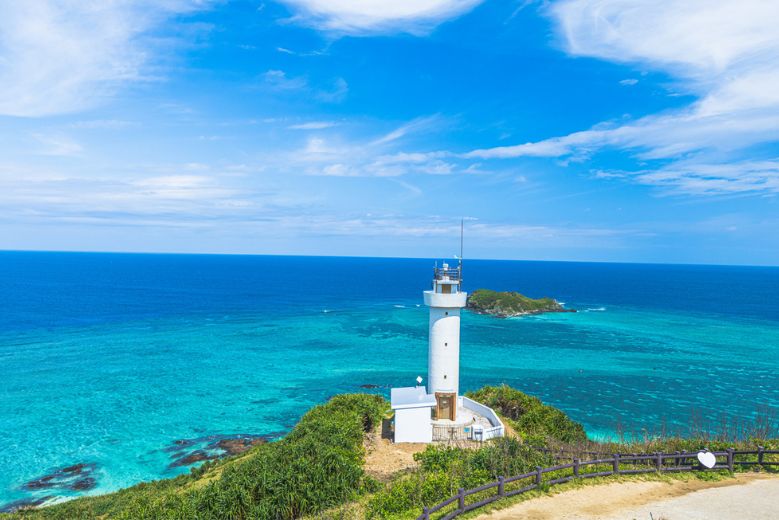 A white lighthouse with a vibrant blue sea at Cape Hirakubozaki on Ishigaki Island