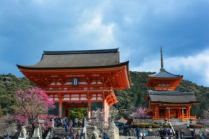A red temple in Kyoto city, with several tourists around, staying at the hotels in Kyoto